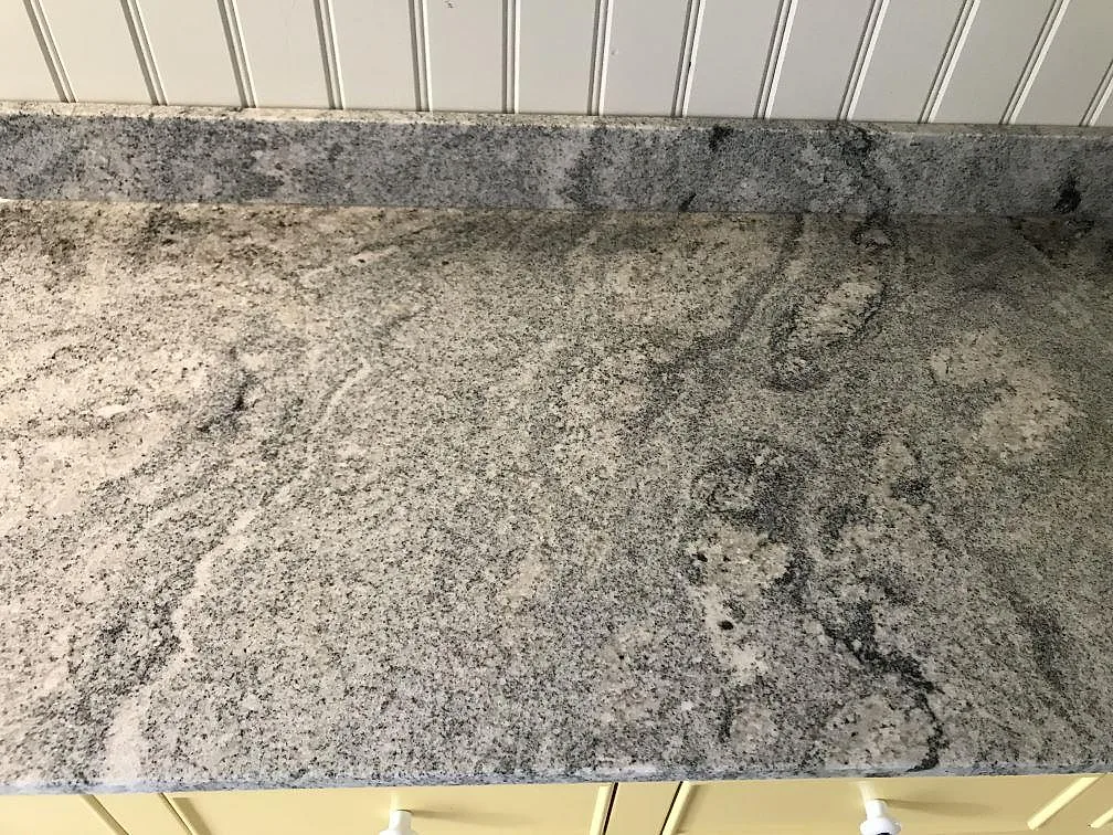 Köksbänkskiva i Viscont White granit, polerad, med kraftig grågrön ådring längs en rak bänklinje i ett kök i Helsingborg.