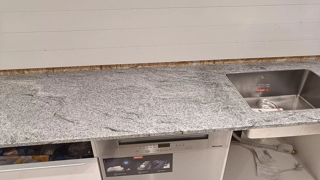 Väggbänk i polerad Viscont White granit med underlimmad rostfri diskho och låg stenkant i Höllviken.