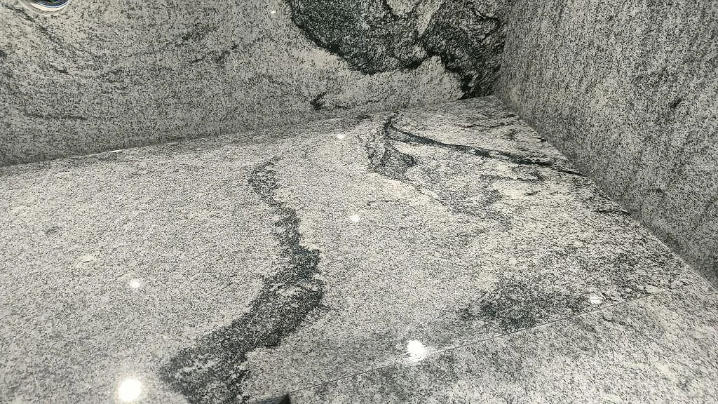 Detalj av grå-svart ådring och kornig struktur i polerad Viscont White granit i ett kök i Hörby.