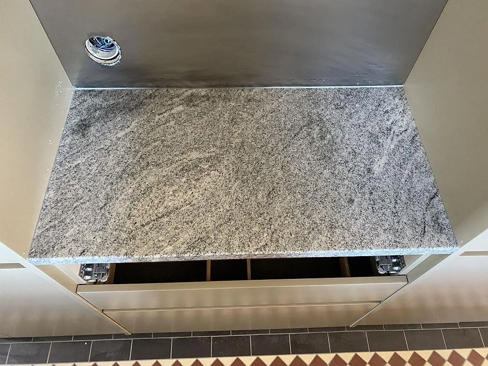 Ovanifrånsvy av polerad Viscont White granit på en mindre köksbänkskiva, med ljus och mörk ådring i Jämshög.