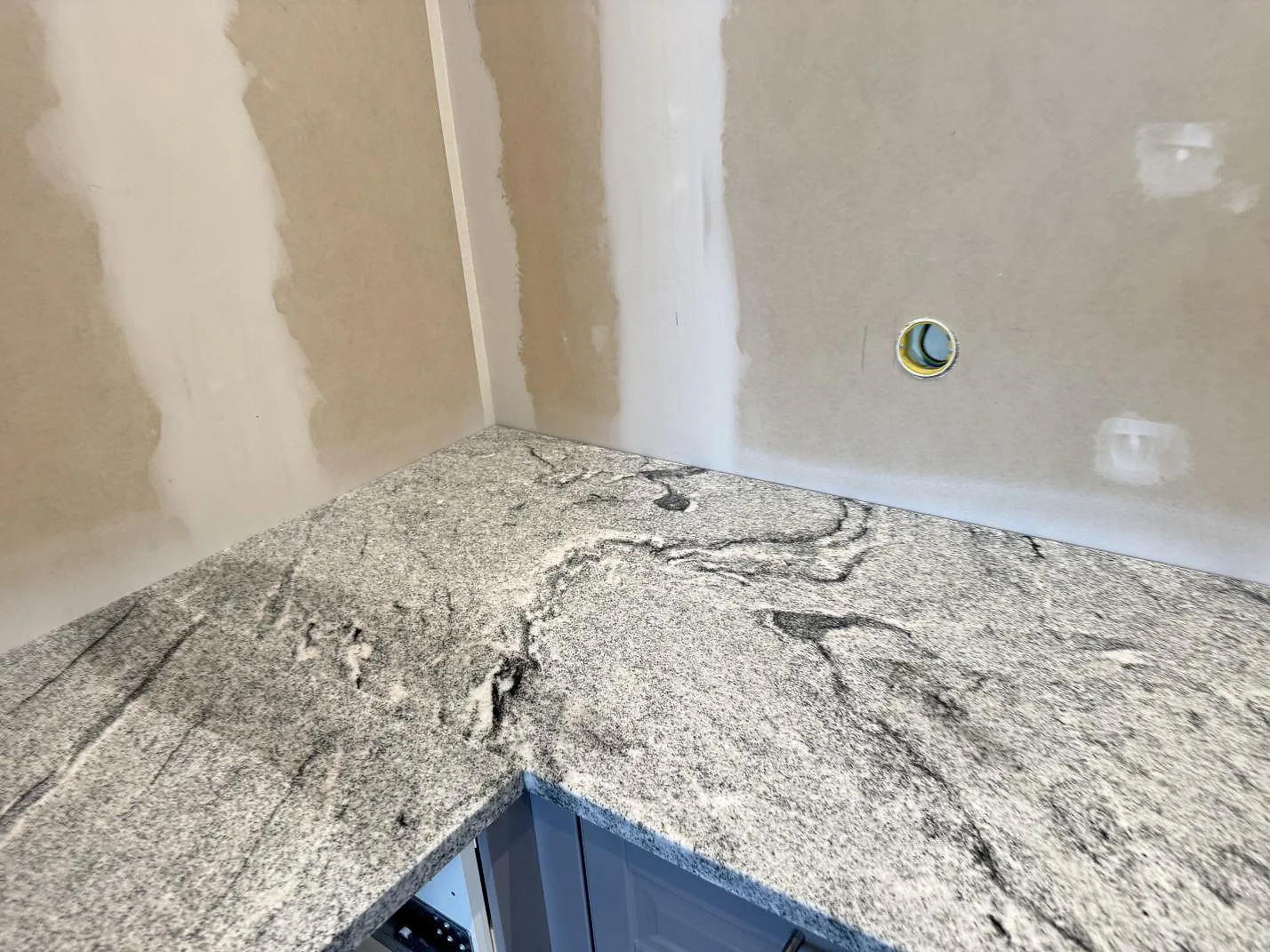 Hörnsektion av köksbänk i polerad granit Viscont White med tydlig ådring i Kävlinge.