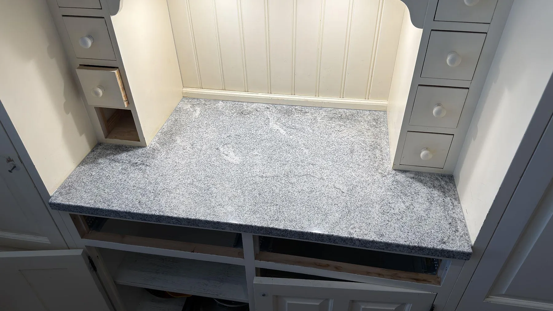 Polerad köksbänkskiva i graniten Viscont White, 30 mm, monterad mellan höga skåpsidor i ett kök i Kista.