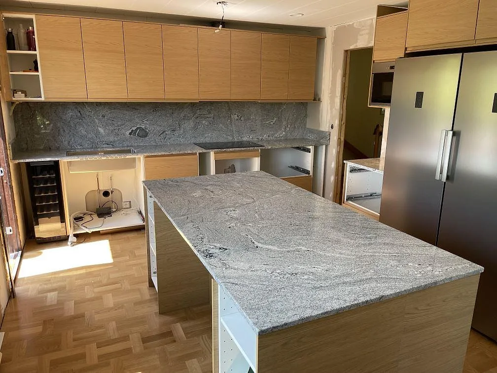 Kök i Mariefred med polerad Viscont White granit på köksö, bakre bänkskiva och stänkskydd upp till överskåpen.