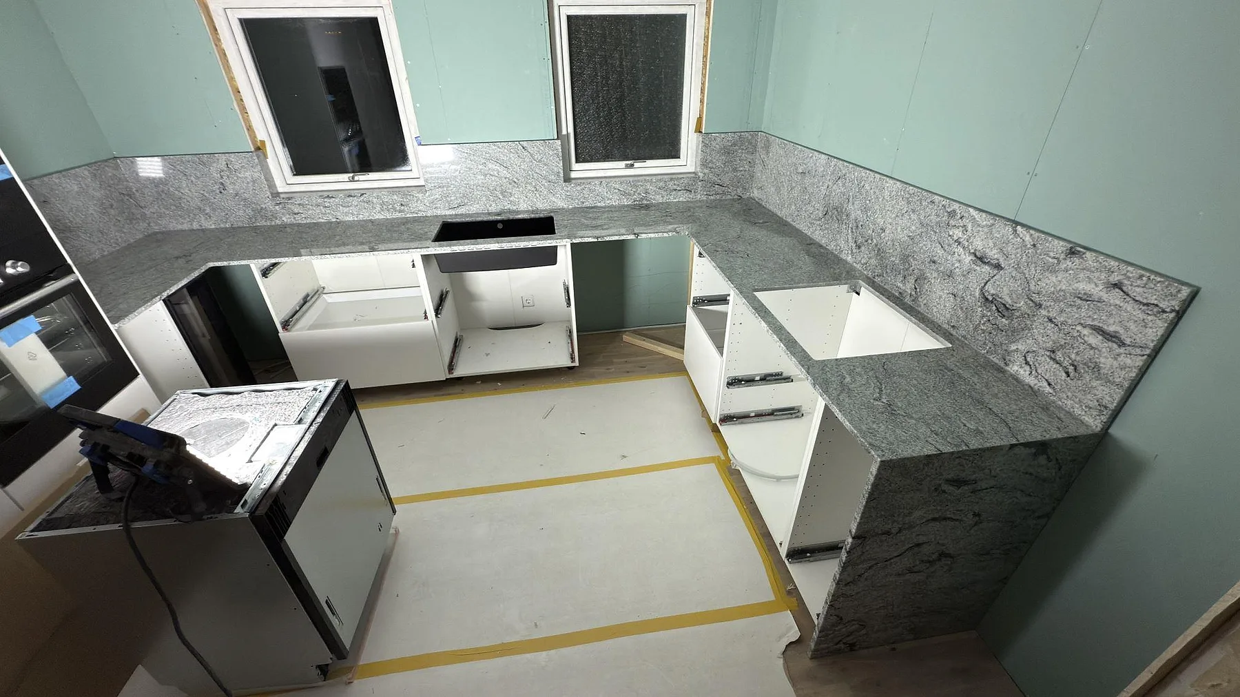 Köksbänkskiva i polerad Viscont White granit med stänkskydd och väggnära U-form i ett kök i Nora.