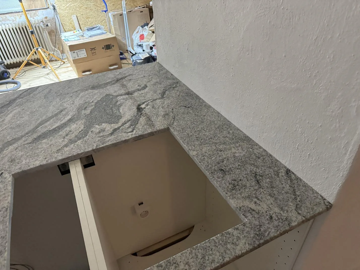 Detalj av Viscont White-granit runt ett rektangulärt hällurtag, polerad yta och vägganslutning i köket i Olofström.