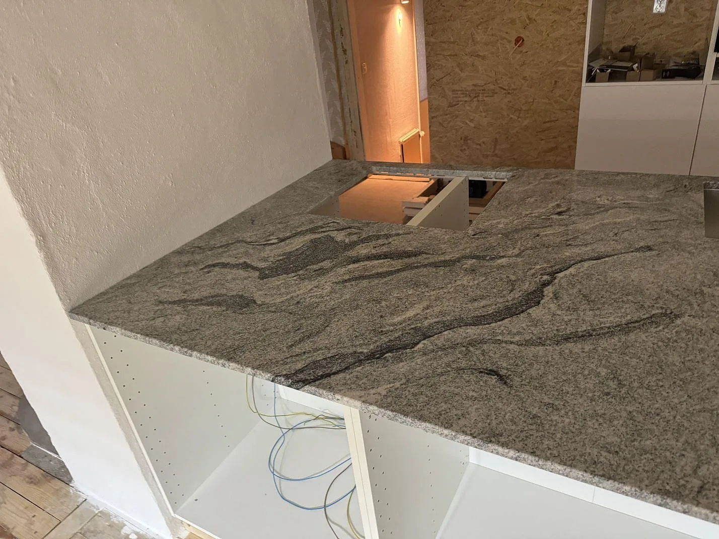Närbild på den polerade Viscont White-granitens grå ådring och hällurtag på köksbänkskivan under montering i Olofström.