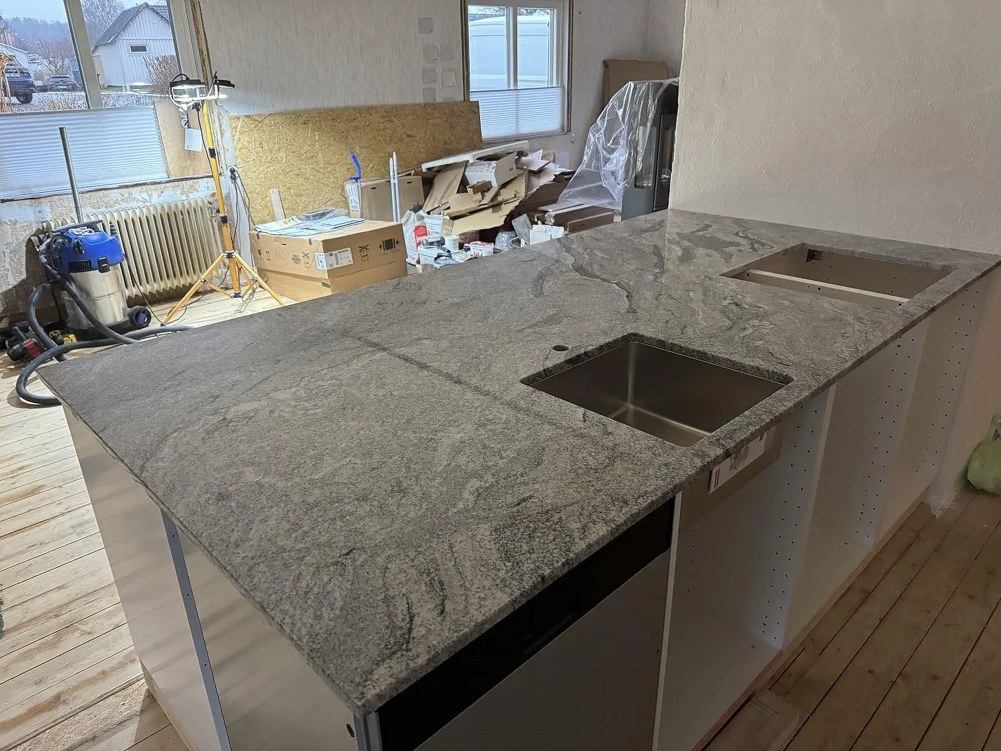 Polerad Viscont White-granit som köksbänkskiva på öppna vita köksstommar, med rostfri diskho och hällurtag i Olofström.