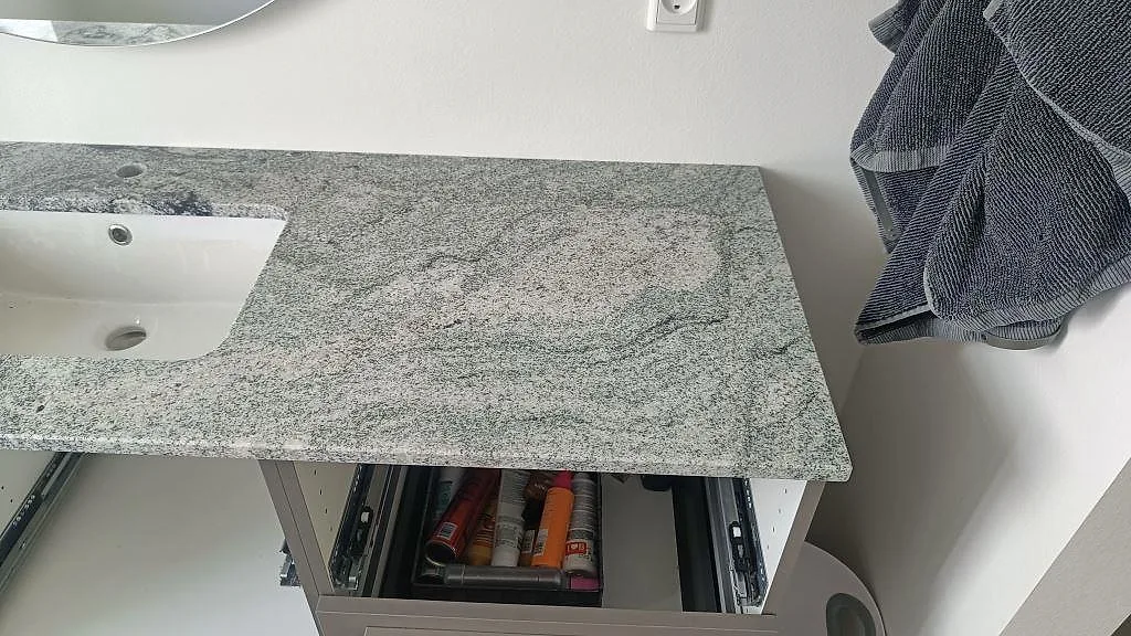 Detalj av badrumsskiva i Viscont White granit med tvättställskant, ljus polerad yta och grå ådring i Ringsted.