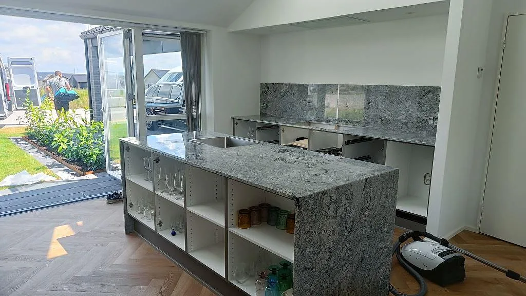 Köksö i 20 mm polerad Viscont White granit med ljus gråådring, neddragen sidoyta och diskhoöppning i Ringsted.