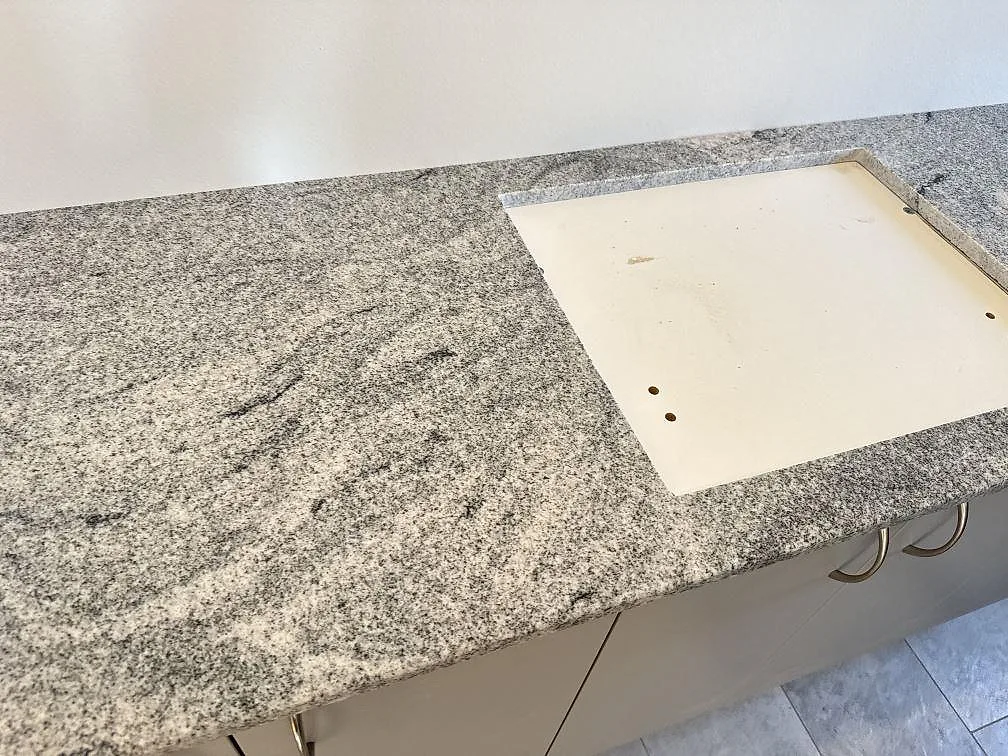 Badrumsbänkskiva i polerad Viscont White granit med öppning i skivan och vita stommar i Saltum.