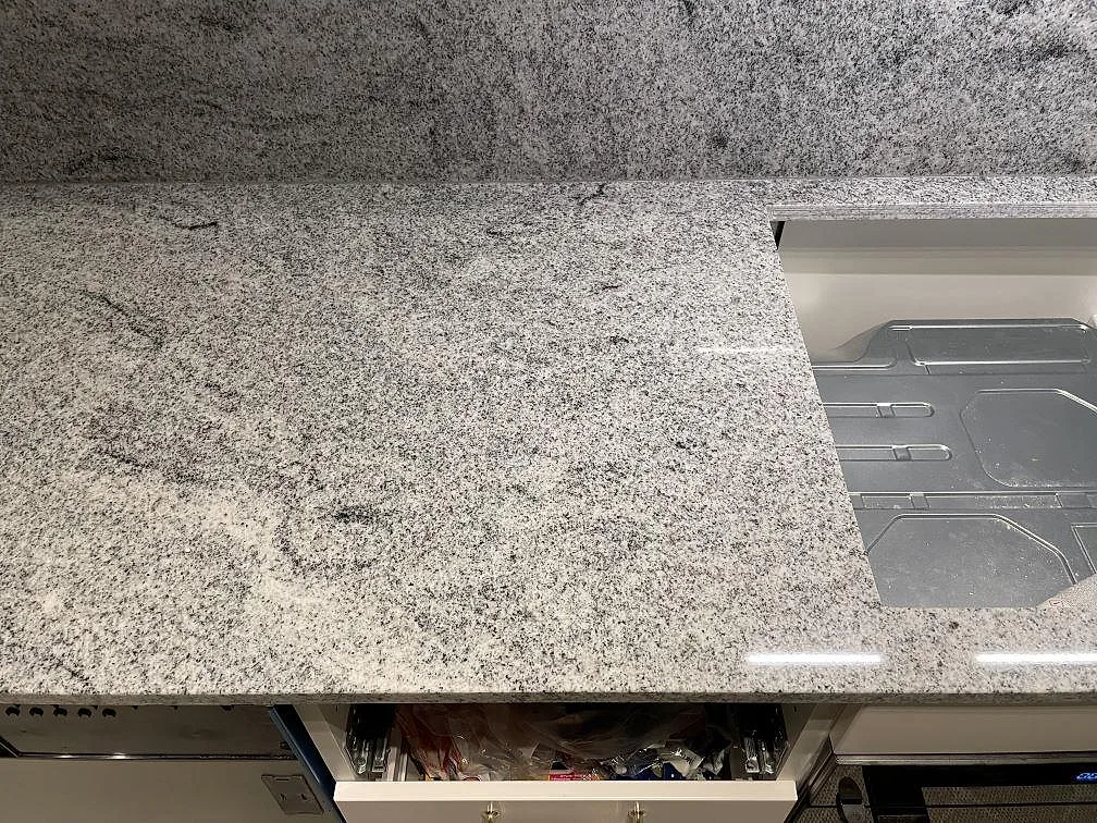 Bänkskiva i polerad Viscont White granit med infälld induktionshäll i ett kök i Sollentuna.