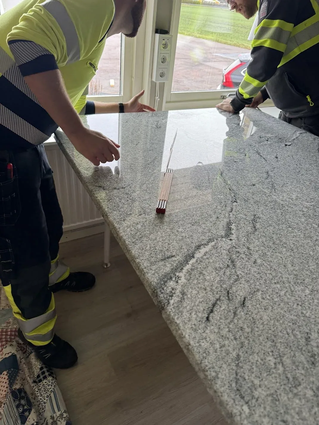 Installatörer justerar en polerad köksöskiva i Viscont White granit med synlig grå ådring i Vallåkra.