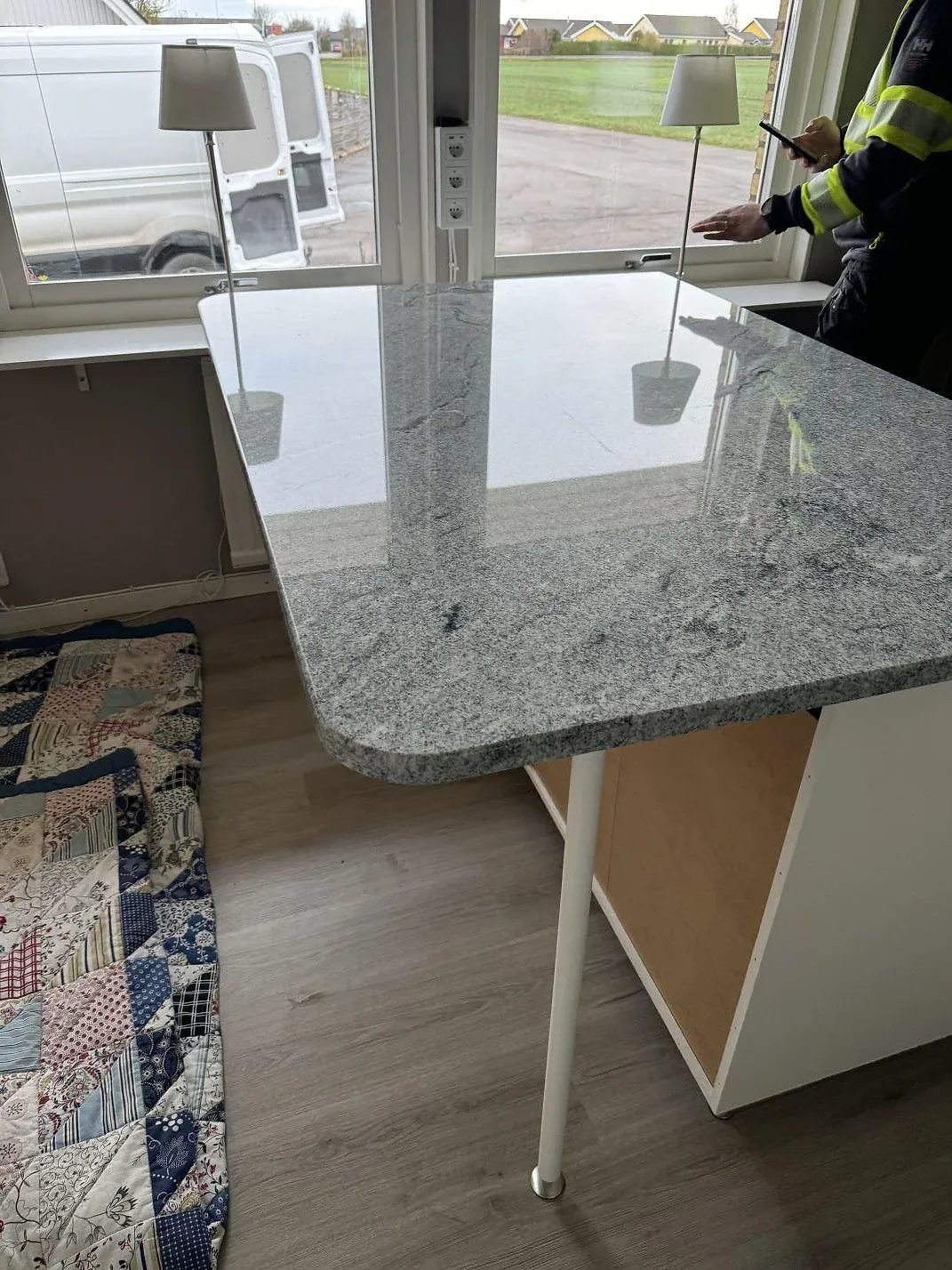 Polerad köksöskiva i Viscont White granit med rundad ände och spegling från fönster i Vallåkra.