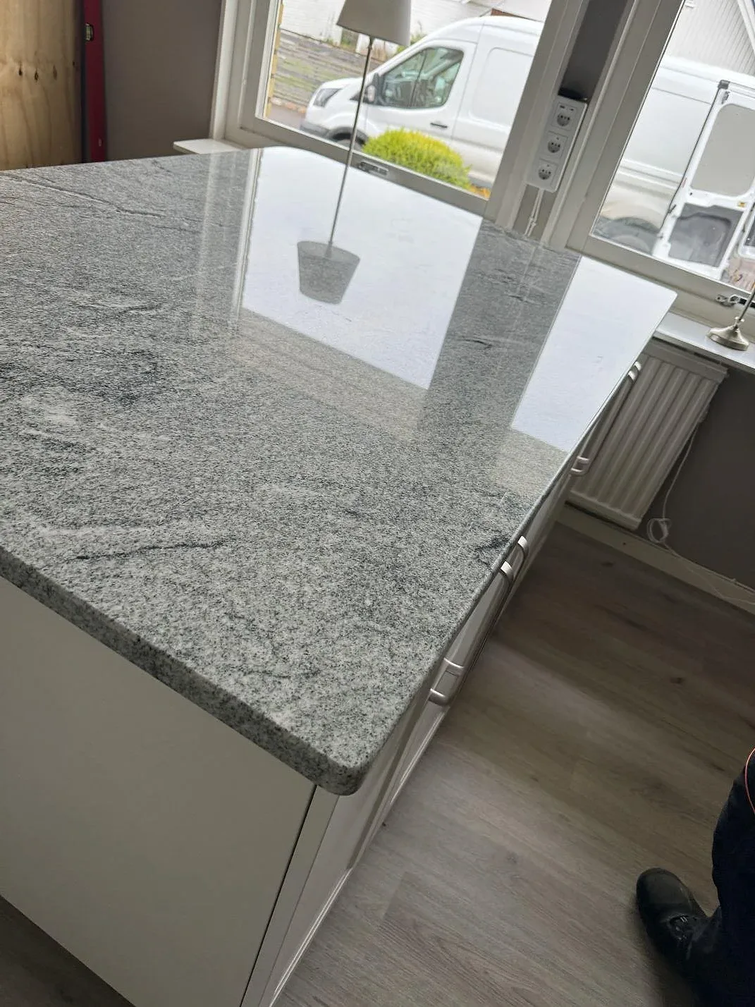 Närbild på 30 mm polerad Viscont White granit på köksö med ljus fönsterreflektion i Vallåkra.