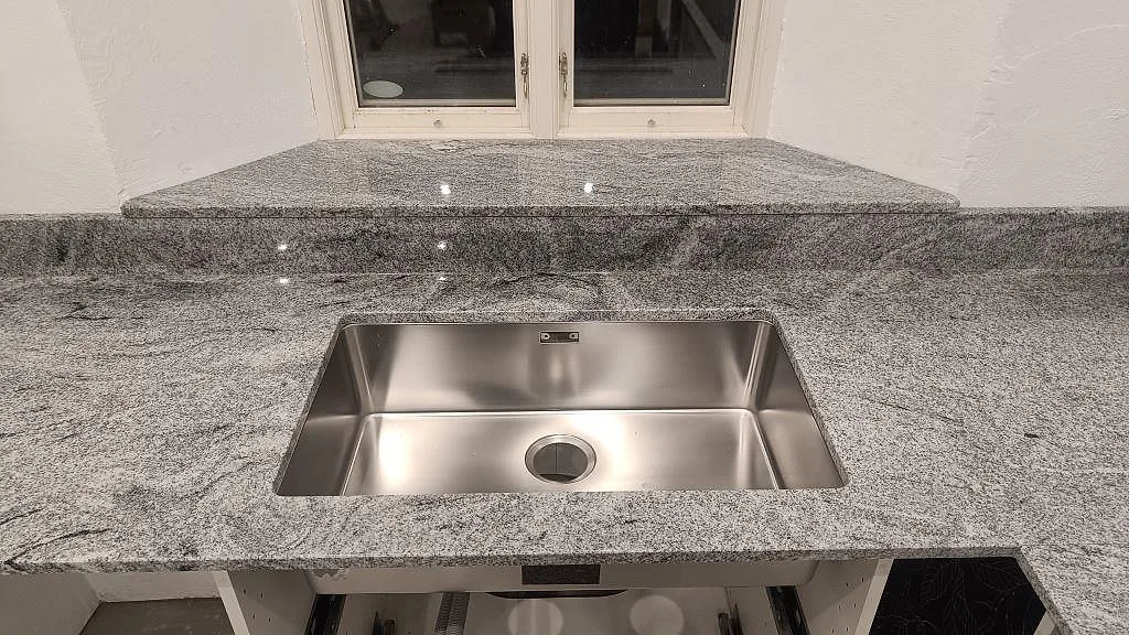 Köksbänkskiva i polerad Viscont White granit med underlimmad rostfri diskho, fönsterbänk och stänkkant i Vellinge.