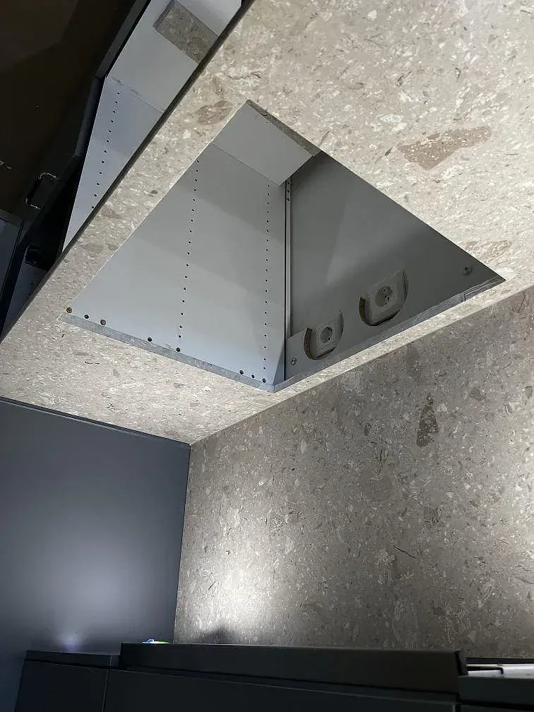 Köksbänkskiva i Terrazzo Perlato Royal med uppvikt stänkkant och uttag i ett kök under montering i Malmö.