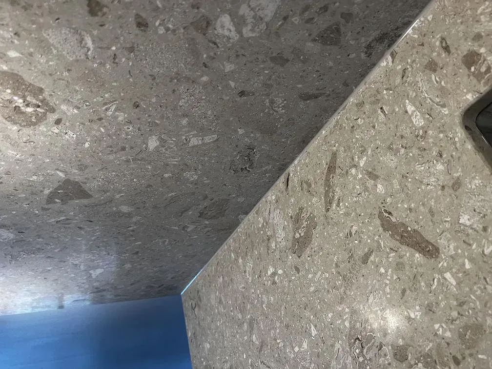 Detalj av ytan på Terrazzo Perlato Royal med skyddsfilm under montering, matt ljus terrazzo med marmorinslag, i ett kök i Malmö.