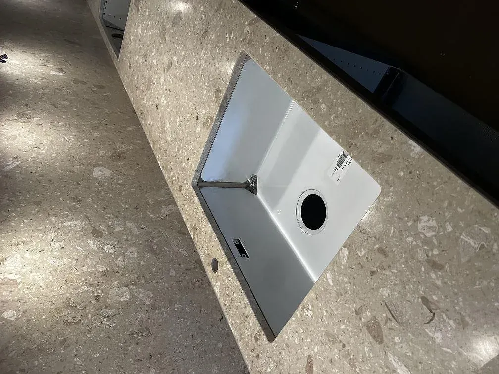 Underlimmad rostfri diskho i en bänkskiva av Terrazzo Perlato Royal, matt yta, sett ovanifrån i ett kök i Malmö.