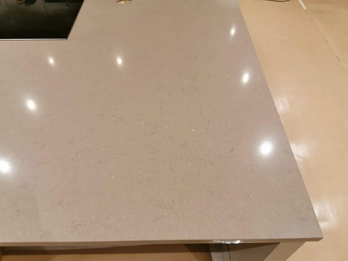 Närbild på den polerade greige ytan i Silestone Coral Clay som visar stenens lågmälda ådring i ett kök i Kristianstad.