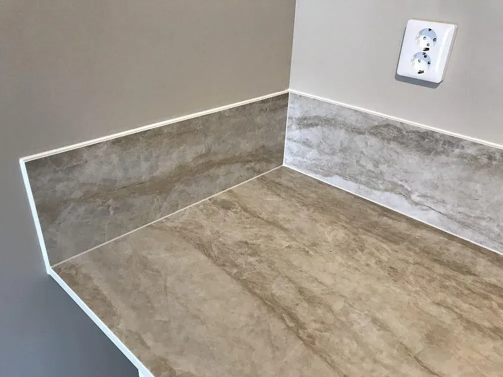 Köksbänkskiva i Dekton Arga, polerad keramik, med uppvikt stänkkant i samma sten i ett kök i Lomma.