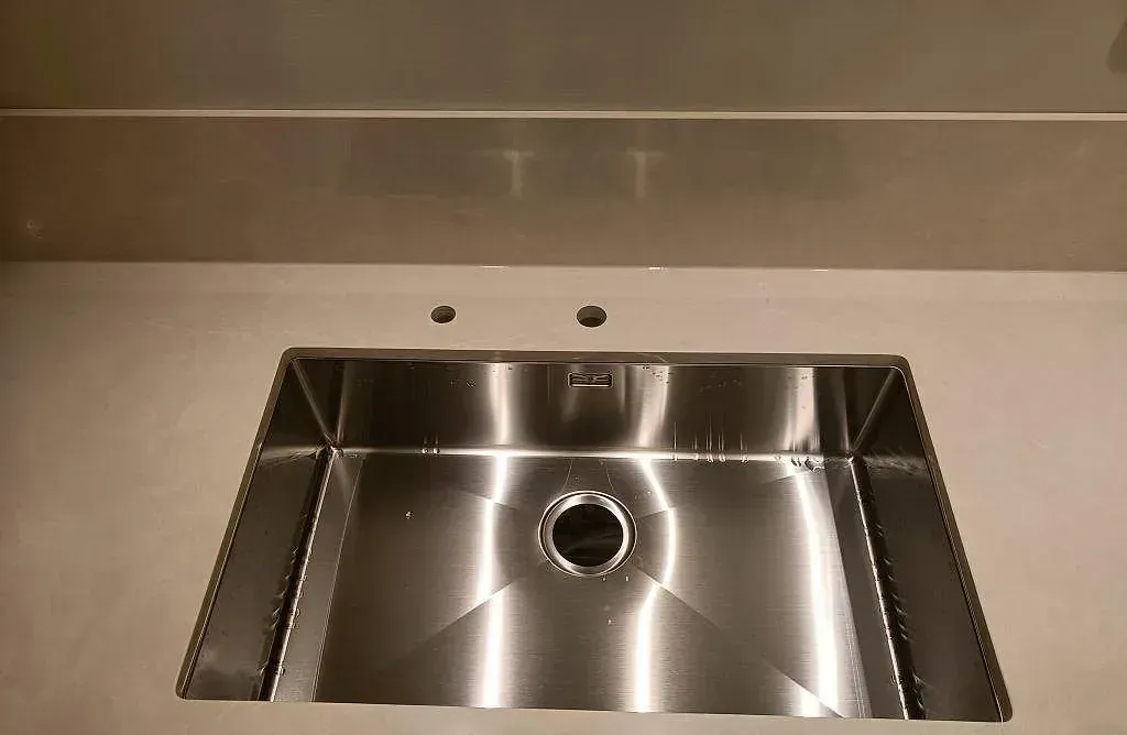 Köksbänkskiva i matt Jura Grey kalksten med underlimmad rostfri diskho i ett kök i Limhamn.